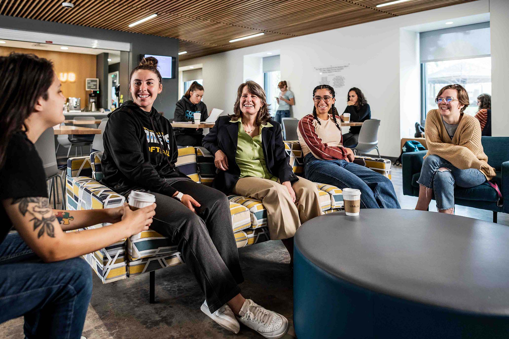 College students socializing with professor in coffee shop