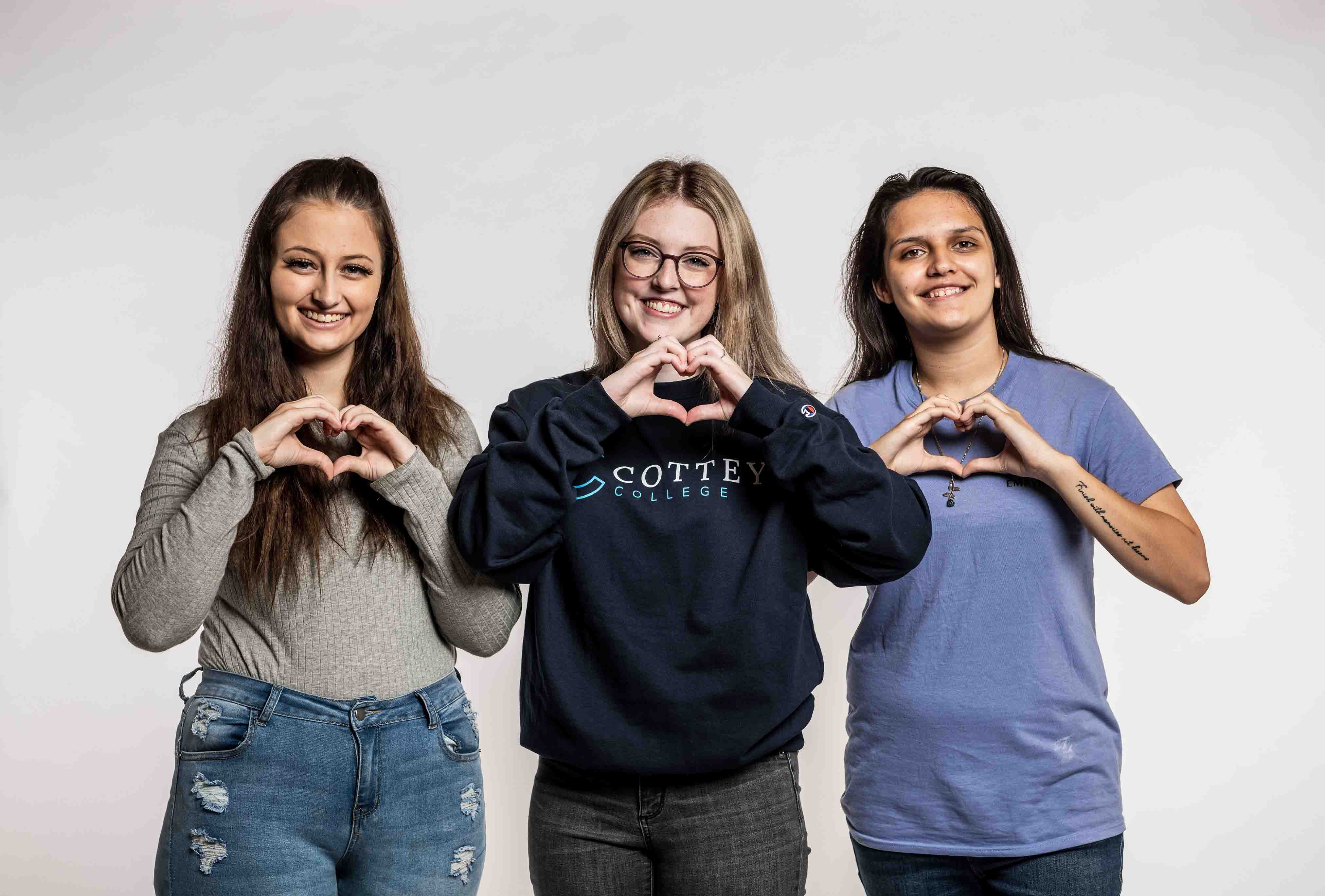 Group of Cottey College students making heart hands and smiling
