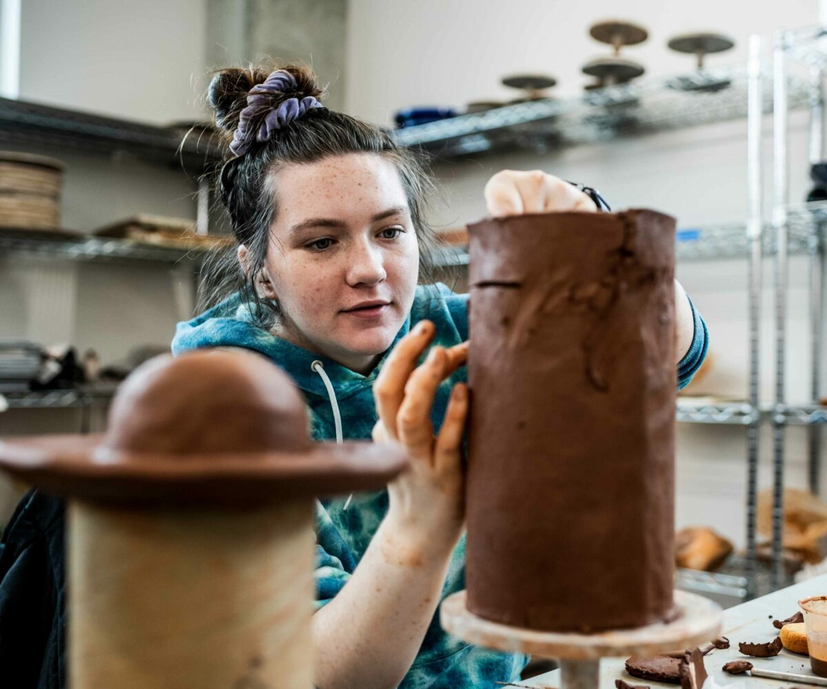 Cottey College student sculpting a pot in the pottery studio