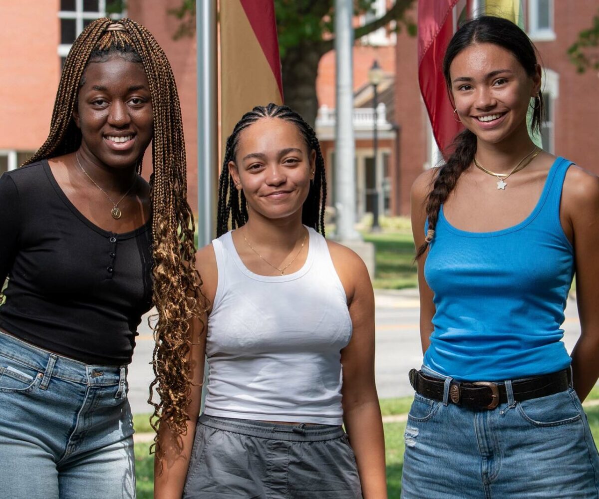 Three international students smiling in Cottey's flag garden.