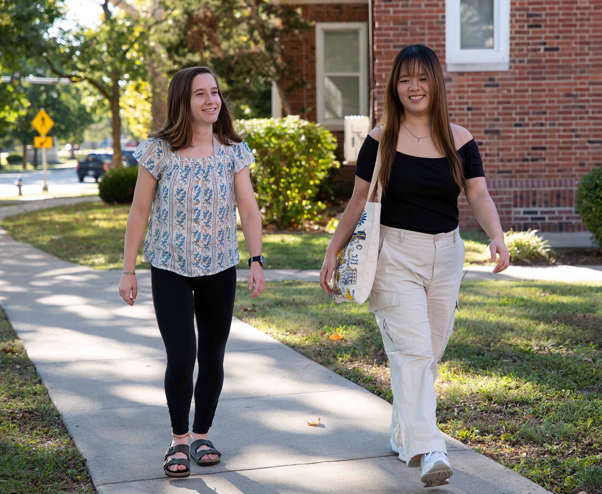 Two students walking to class, enjoying the sunshine
