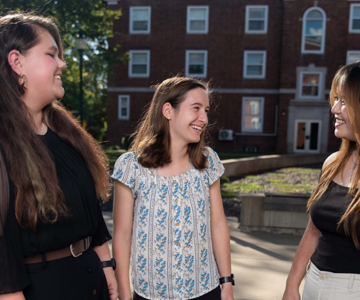 The Cottey College students standing in a campus courtyard, conversing.