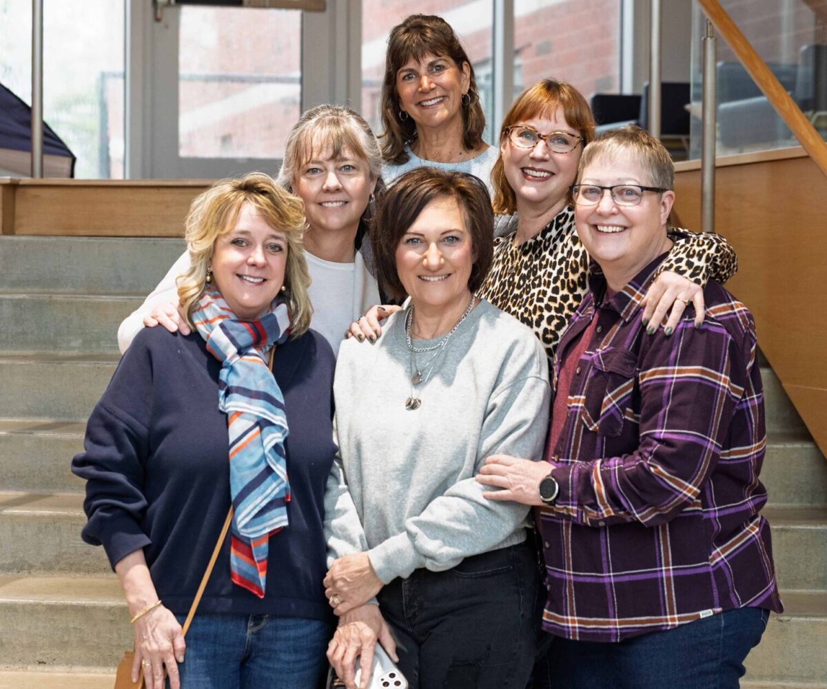 Group of women smiling and posing on staircase.