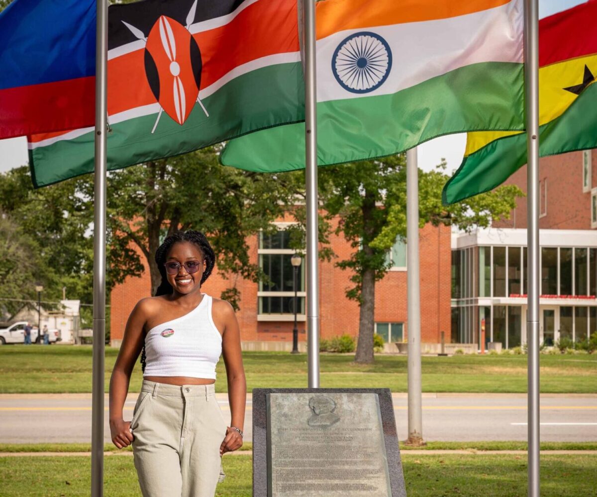 International Cottey student standing in front of flag garden
