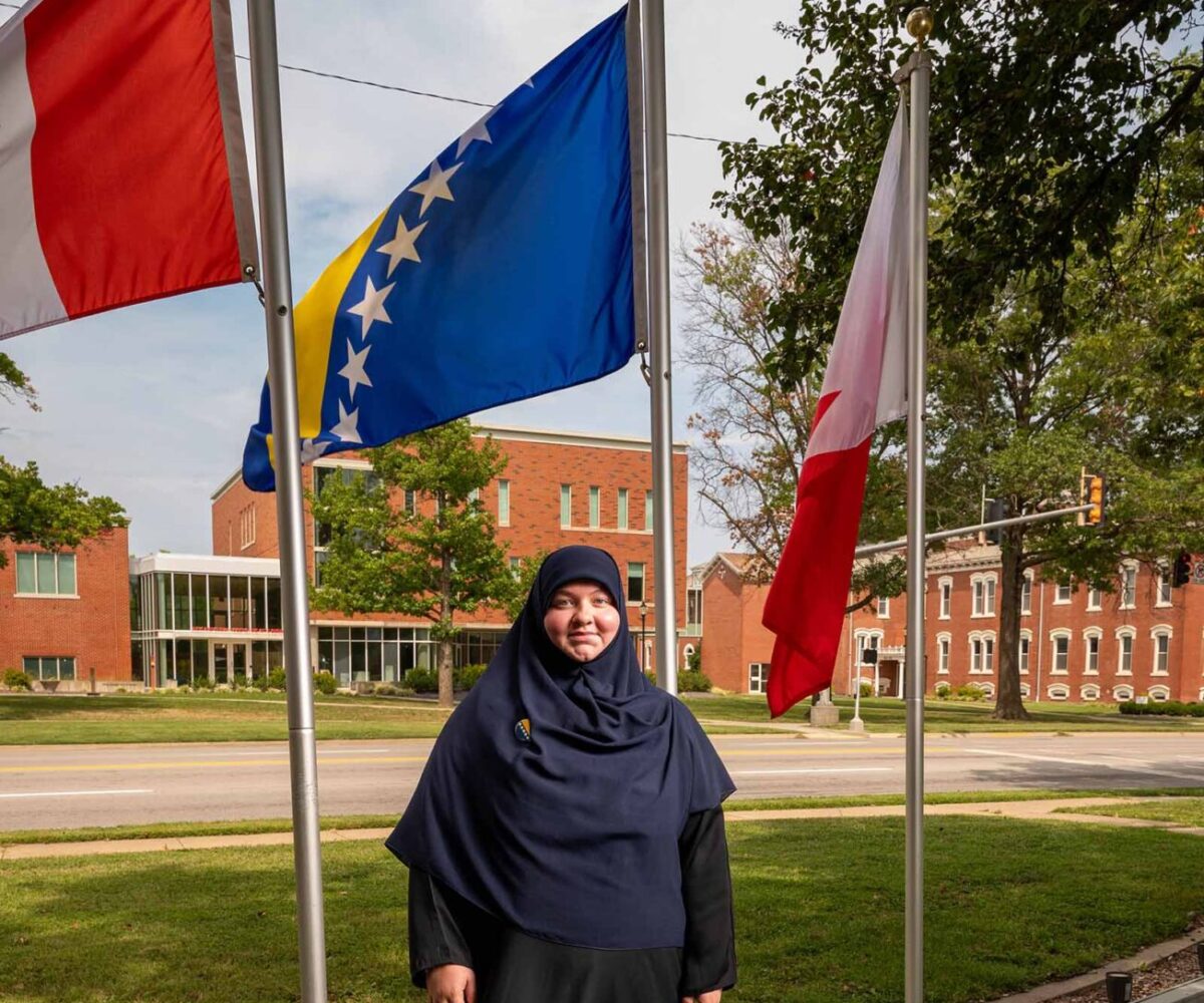 International Cottey student standing in front of flag garden
