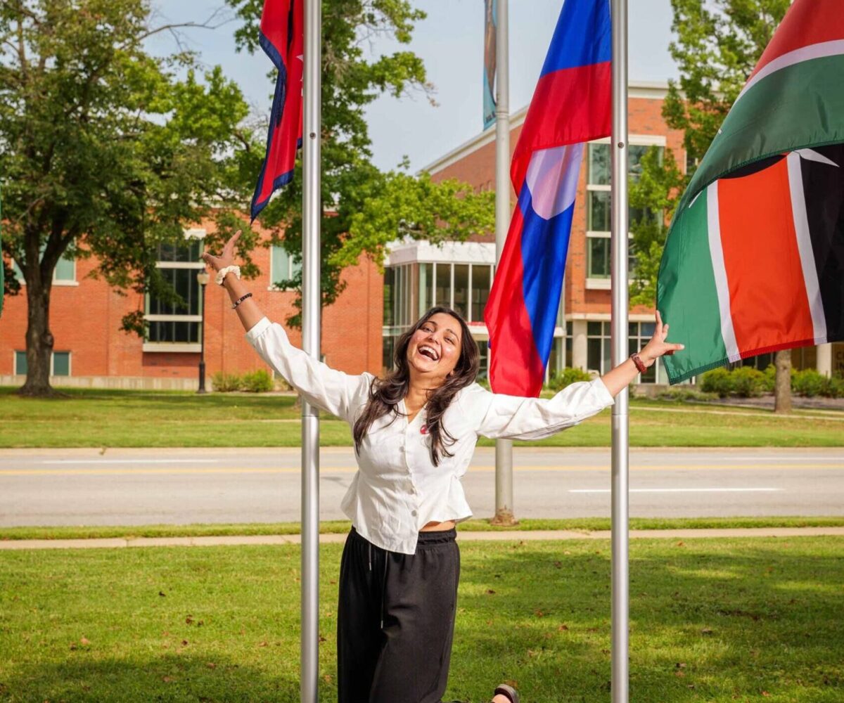 International Cottey student standing in front of flag garden