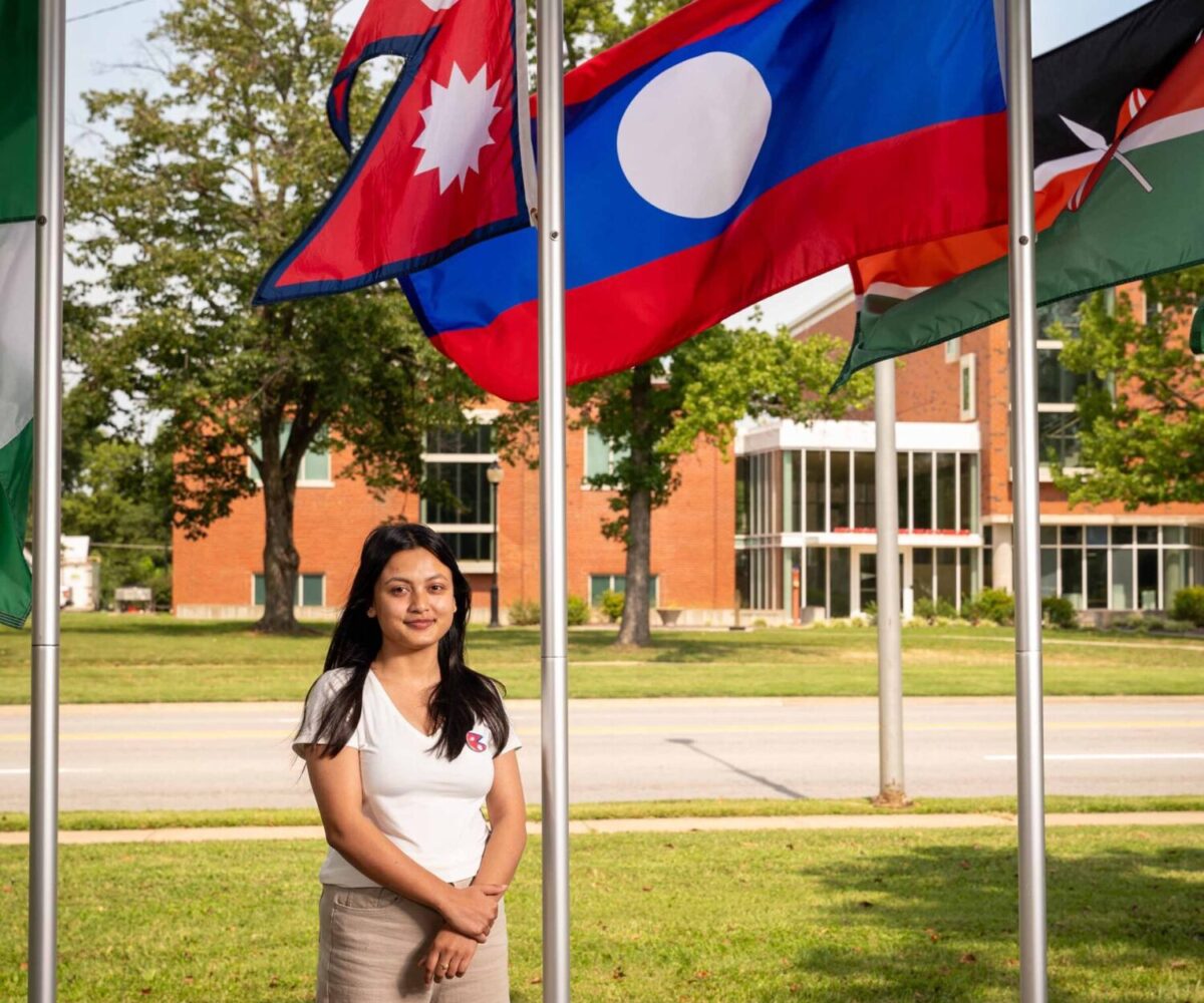 International Cottey student standing in front of flag garden