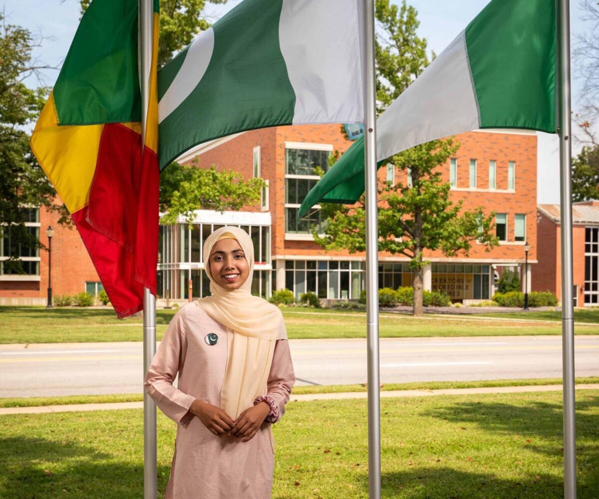 International Cottey student standing in front of flag garden.