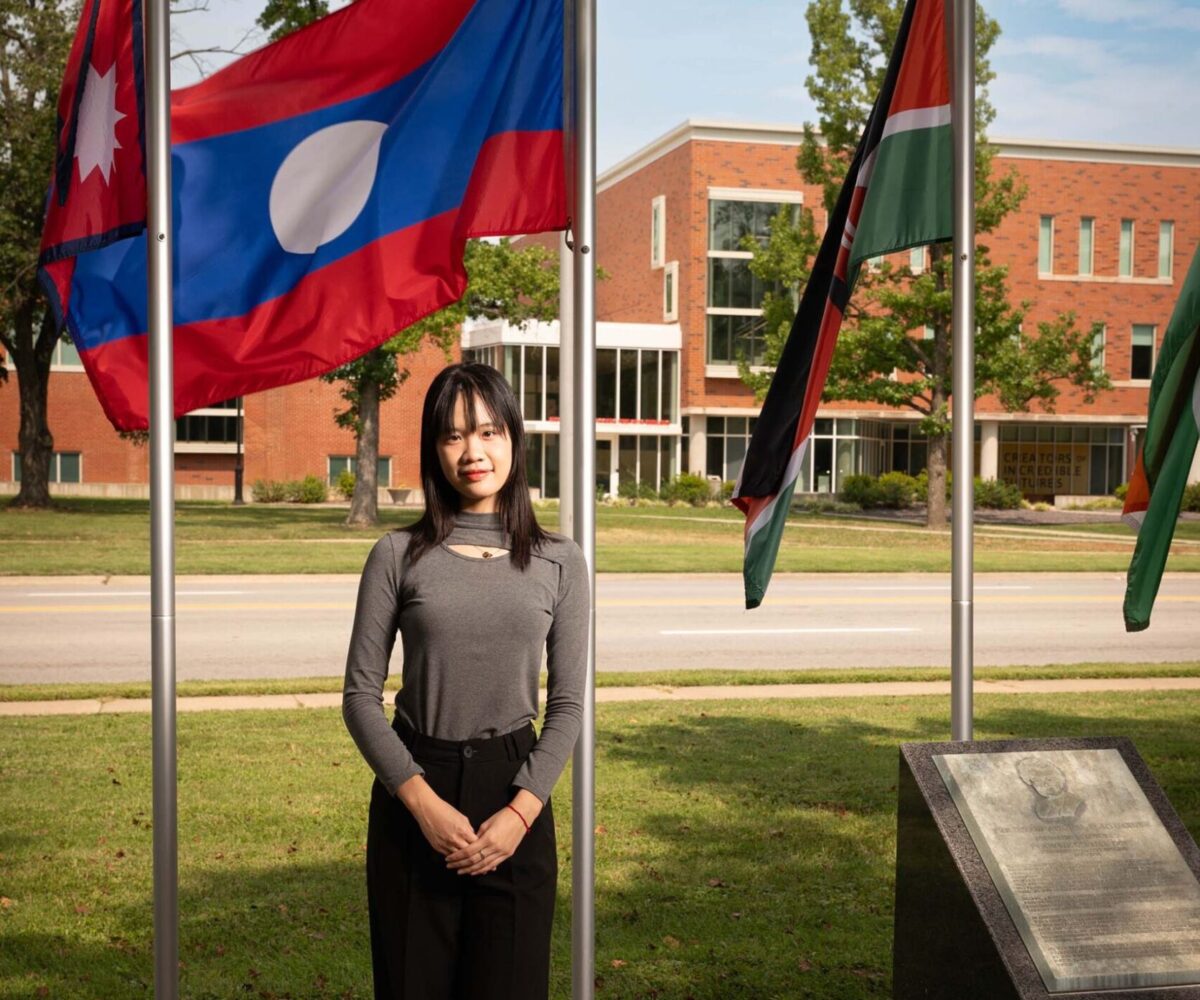 International Cottey student standing in front of flag garden