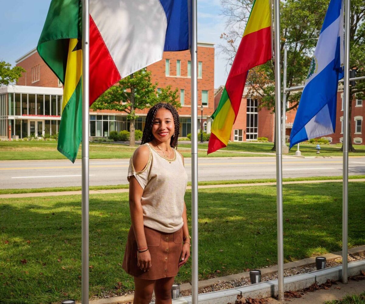 International Cottey student standing in front of flag garden