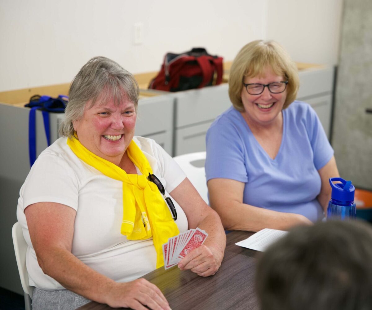 Two women laughing and playing cards.