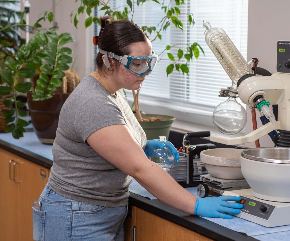 Chemistry student at Cottey College using scientific equipment.