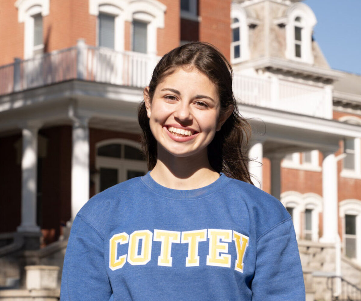 Cottey student smiling in front of historic Main Hall.