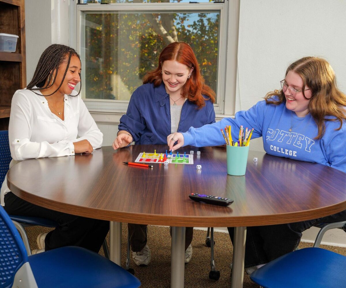 Three Cottey students playing a board game in their suite living room.