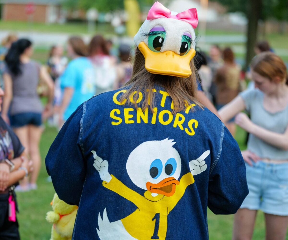 A Cottey student stands in a field of students, wearing a 'Duck Jacket.'
