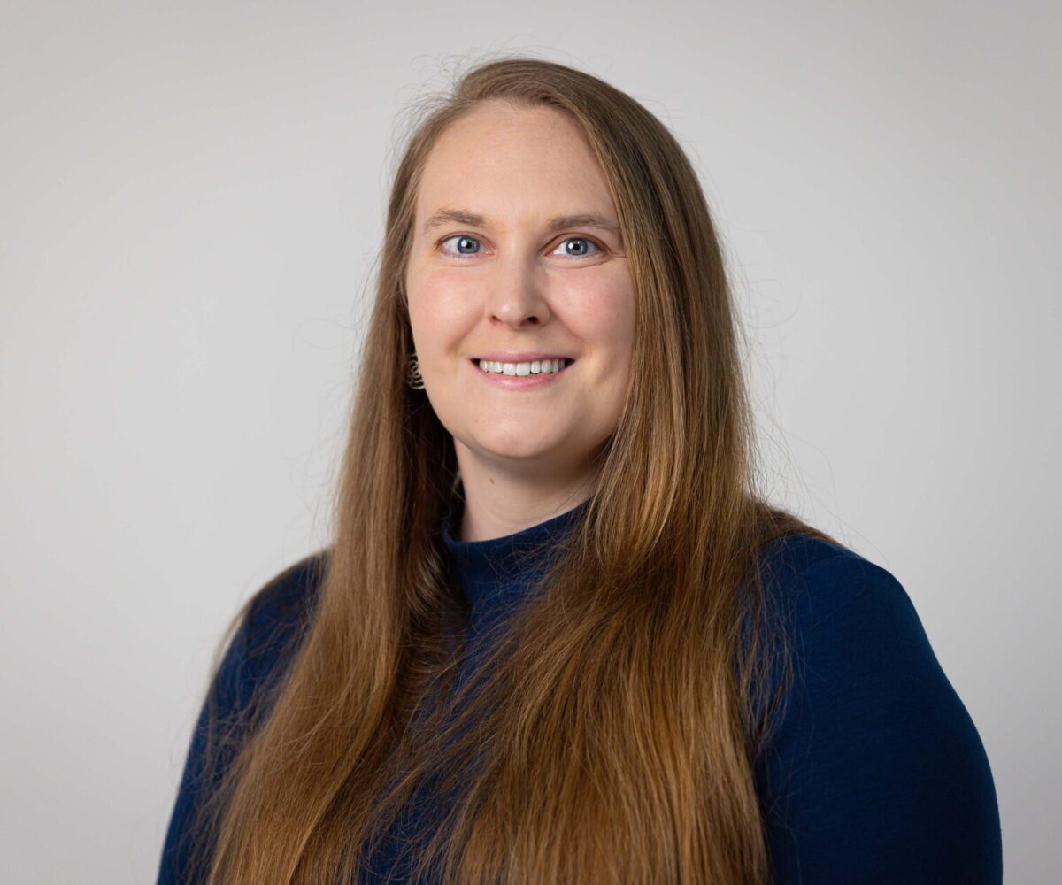 Woman with long hair, wearing navy sweater.